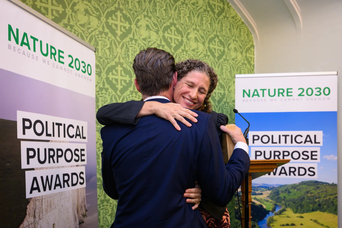 Charlie Maynard is embraced as he collects the award in front of two Nature 2030 banners